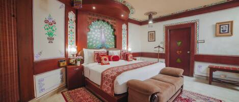 A traditional room with a large bed, a bench, and ornate decorations.