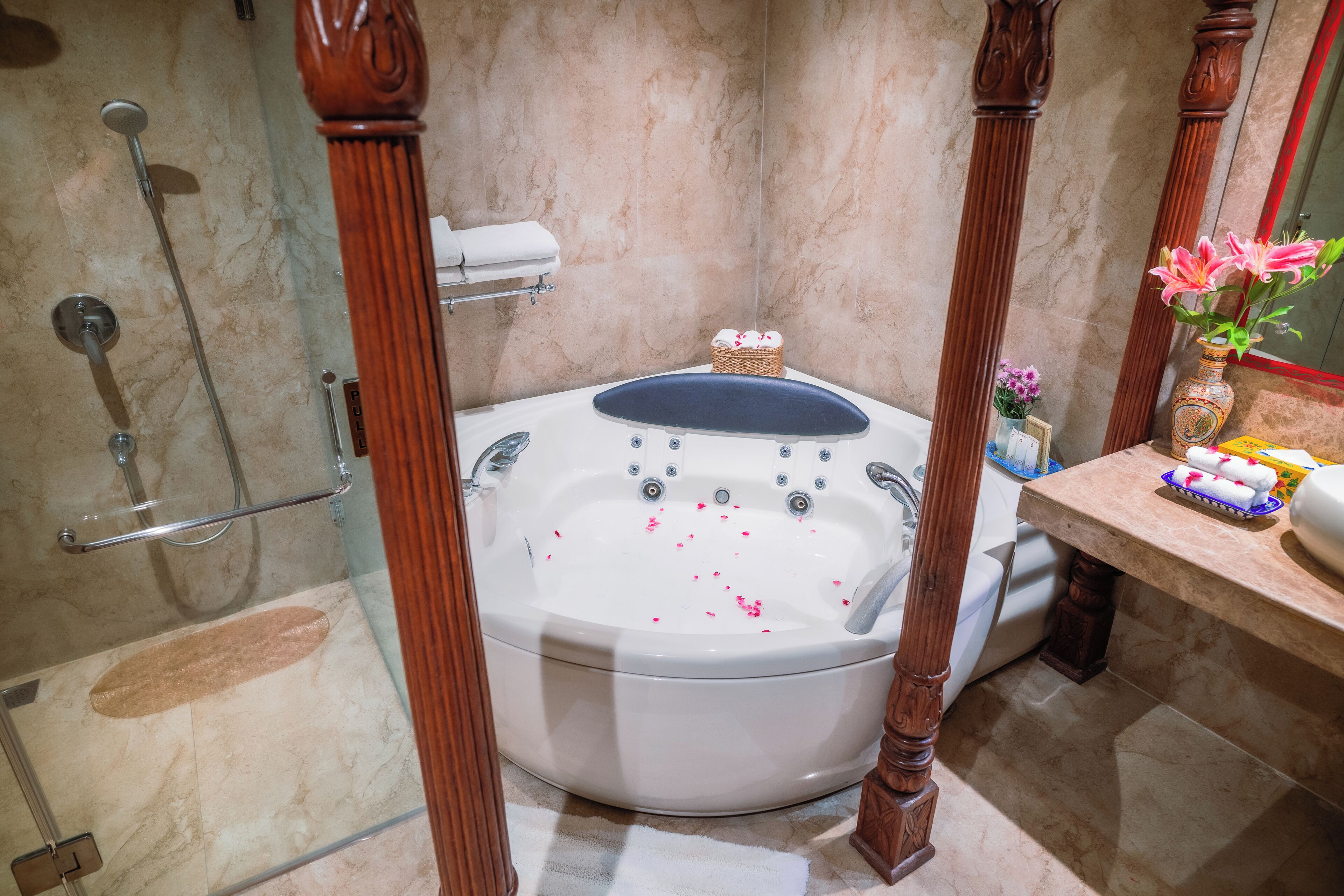 A bathroom with a freestanding bathtub, a shower, and a vanity with a vase of flowers.