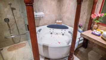 A bathroom with a freestanding bathtub, a shower, and a vanity with a vase of flowers.