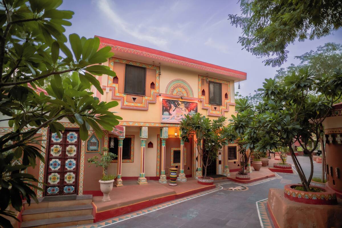 A traditional building with a central entrance, surrounded by potted plants and a tiled courtyard.