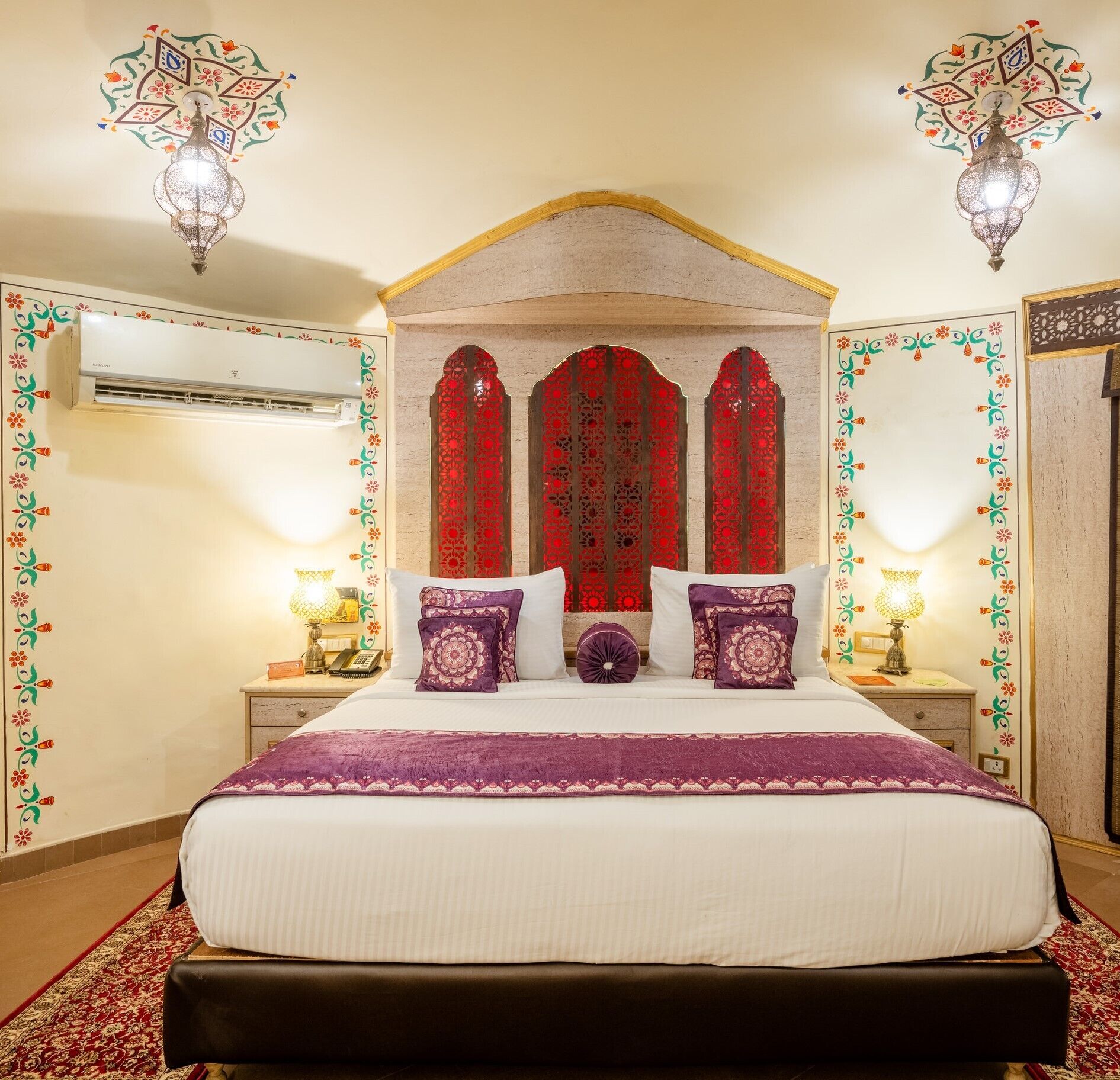 A bedroom with a large bed, decorative wall panels, and two wall-mounted lamps.
