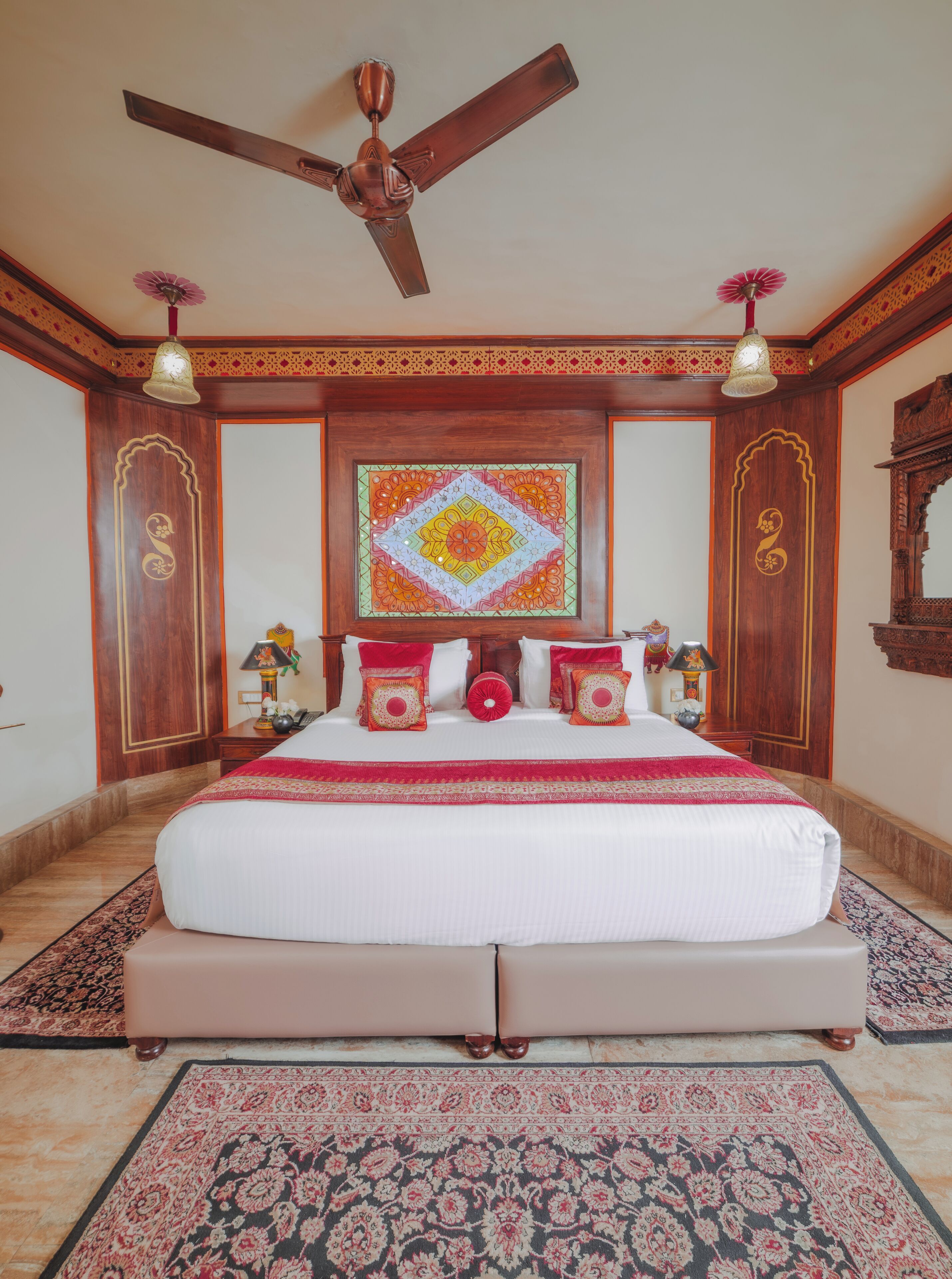 Un dormitorio amplio con una cama grande, un ventilador de techo y un tapiz decorativo.