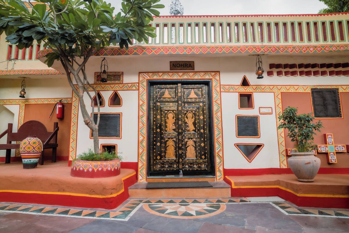 A traditional building with a large ornate door, a sign reading "NOHRA", and a tiled floor with geometric patterns.