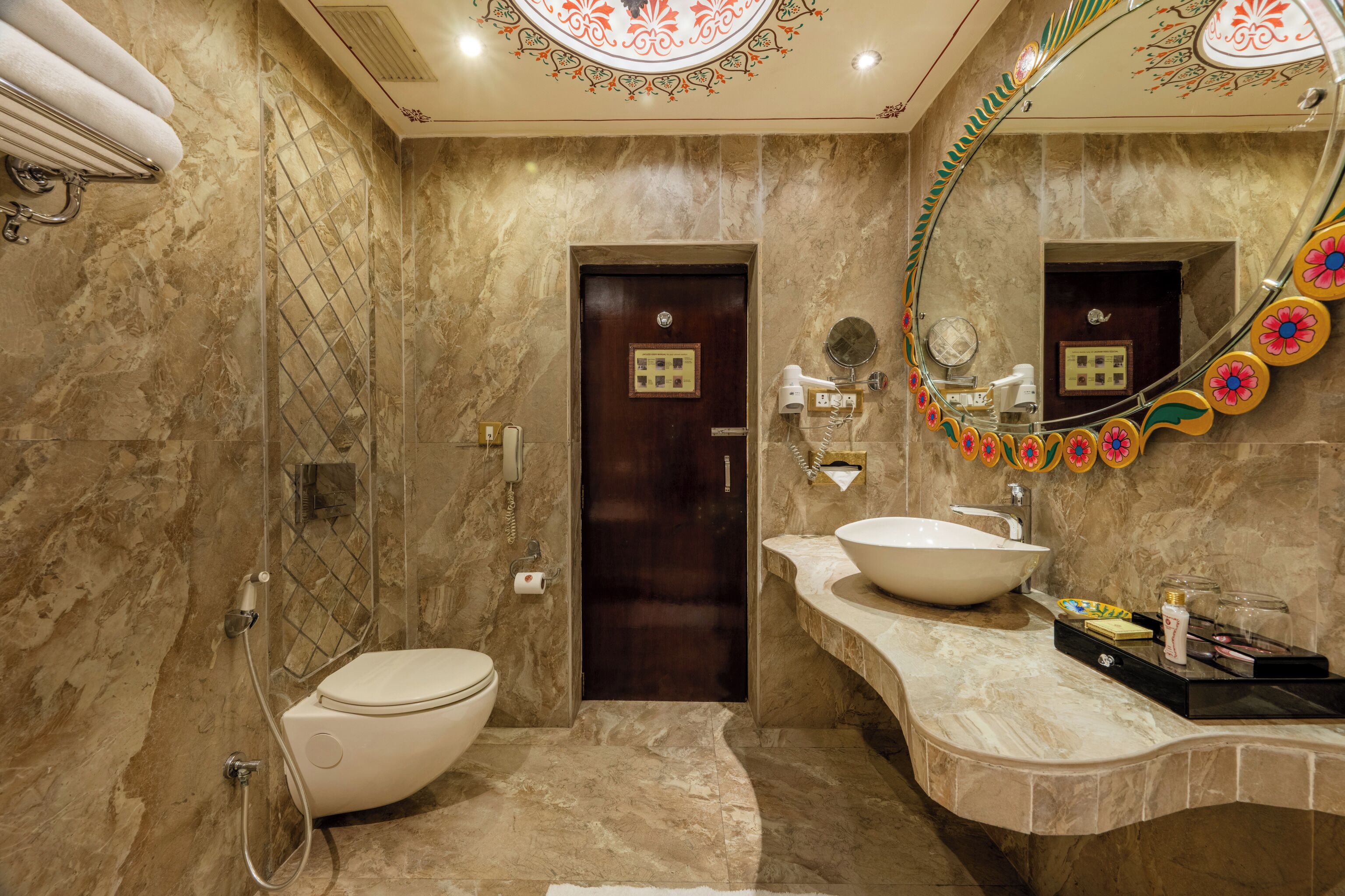 Une salle de bain moderne avec un sol en marbre, un lavabo blanc et un grand miroir doté d’un cadre décoratif.