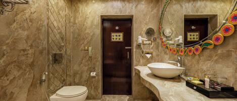 A modern bathroom with a marble floor, a white sink, and a large mirror with a decorative frame.