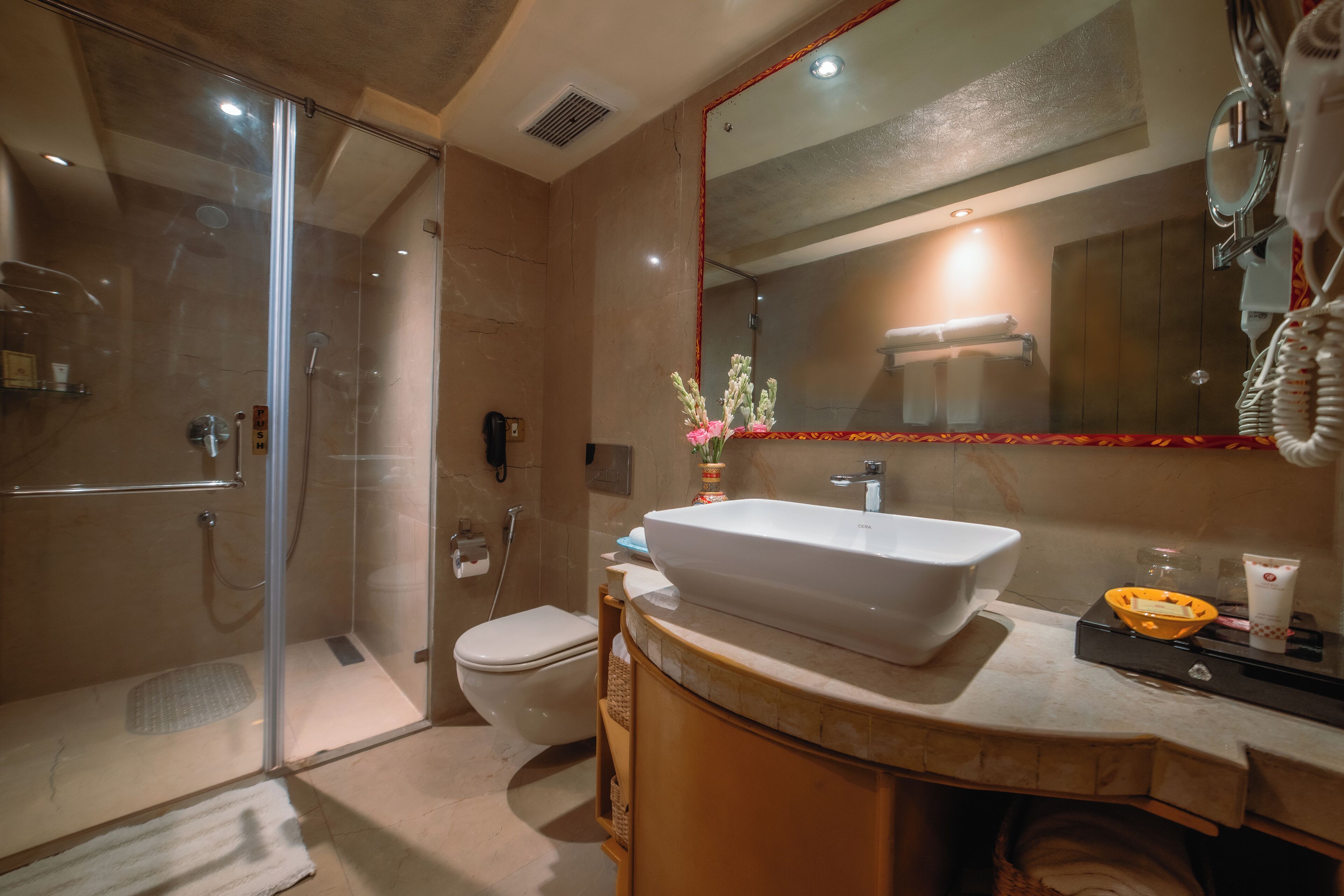 Un baño moderno con ducha de vidrio, lavamanos blanco y un espejo grande.