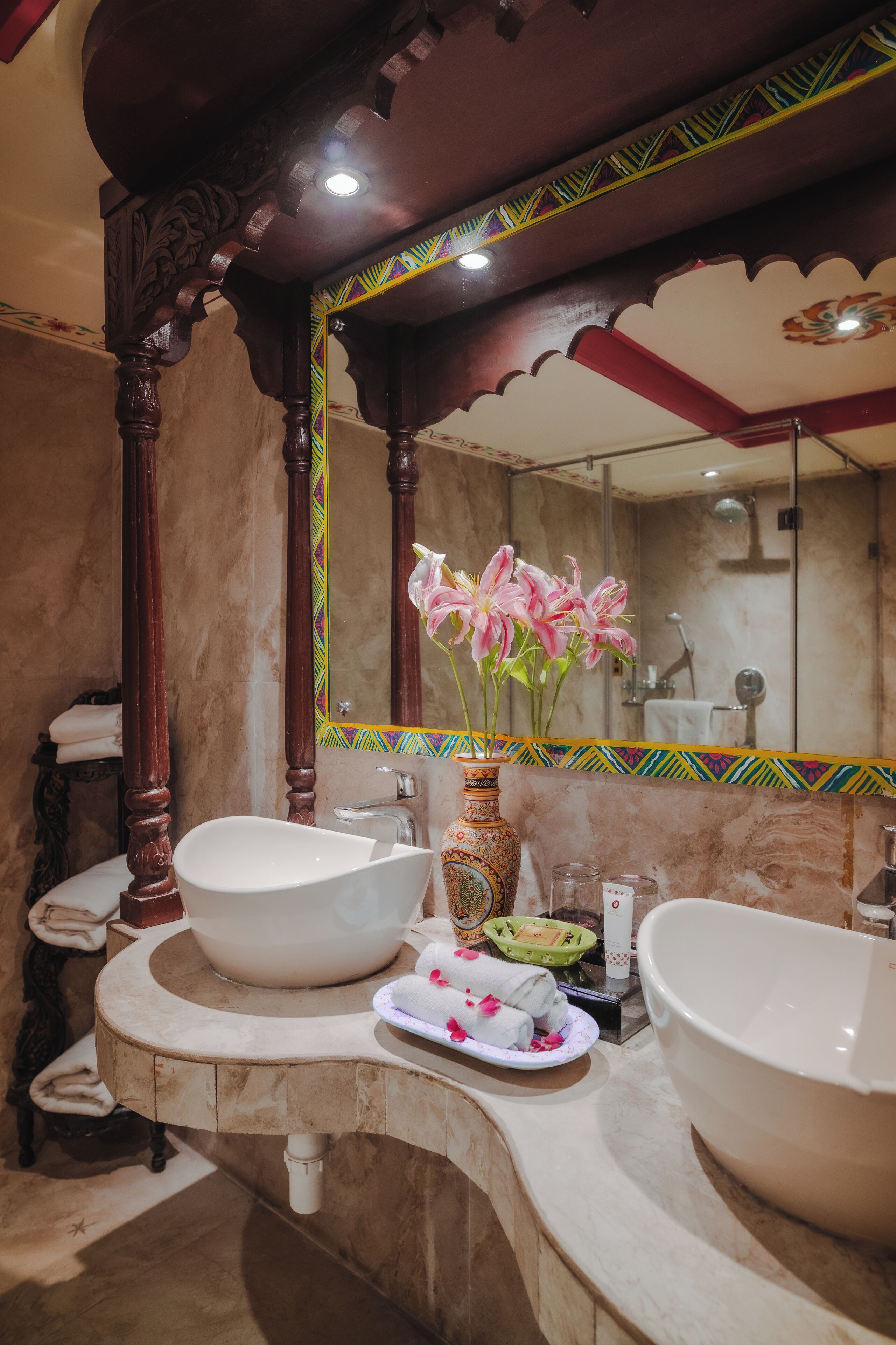 A bathroom with two sinks, a large mirror, and decorative elements including a vase with flowers.