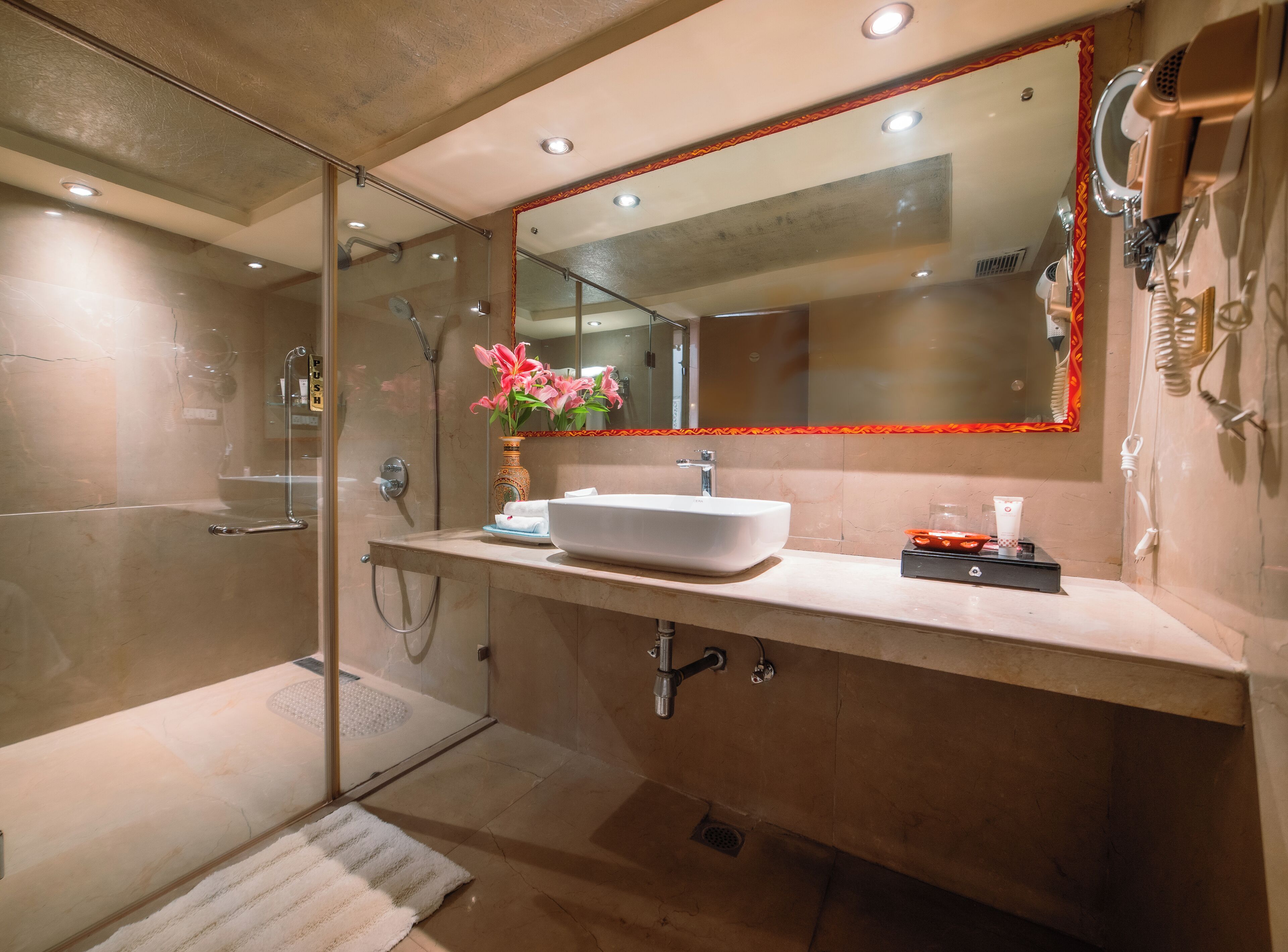 A modern bathroom with a glass-enclosed shower, a large mirror, and a white sink.