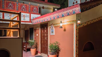A traditional building with a red and yellow facade, a wooden door, and a tiled entrance.