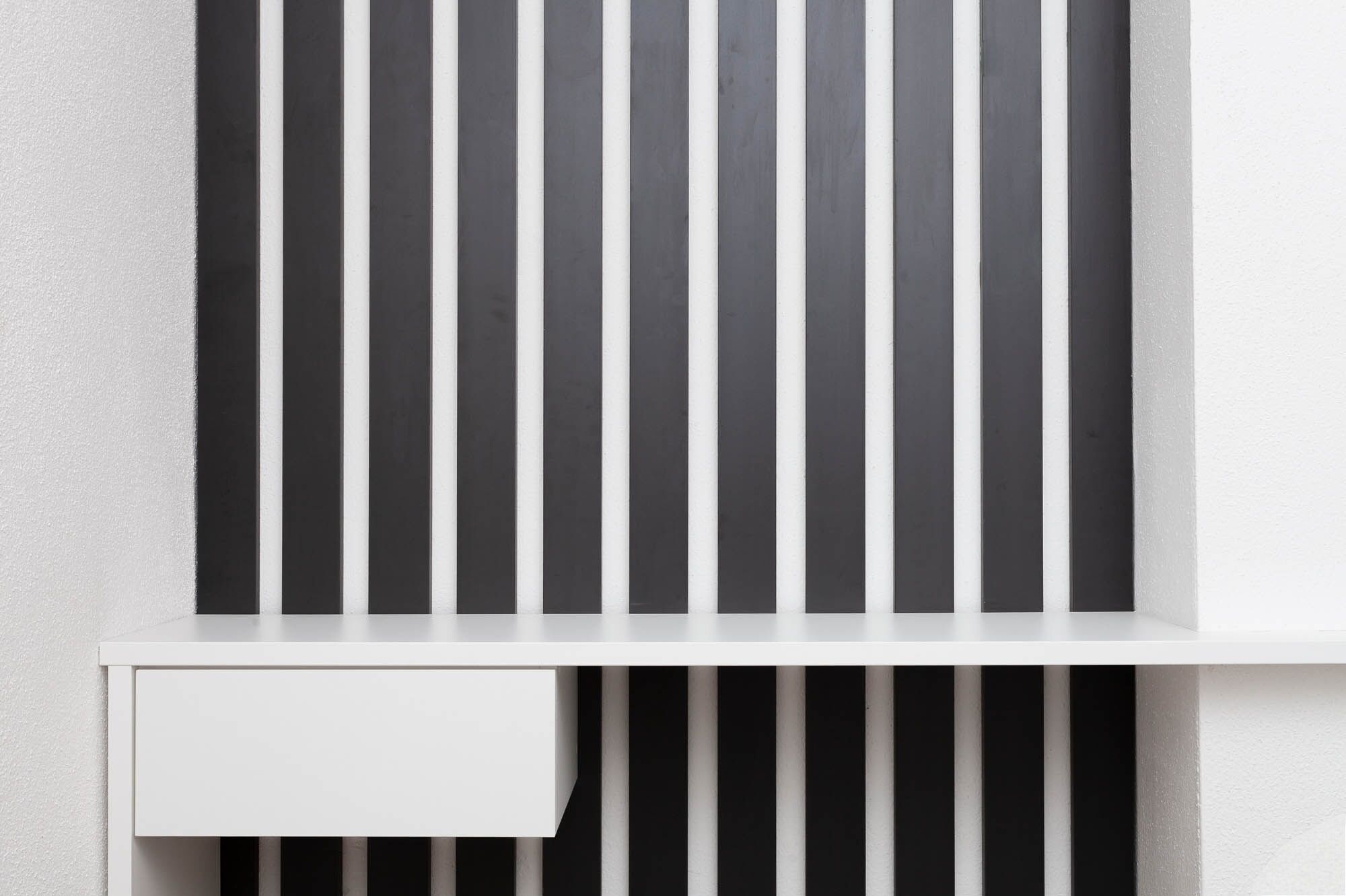 A white wall with vertical black and white stripes.