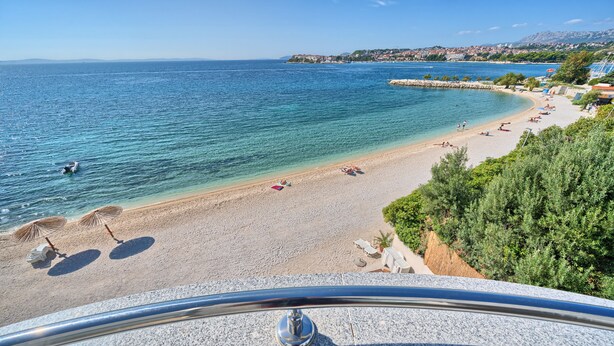 A coastal beach with clear waters, sun loungers, and umbrellas. - Sunset Split Rooms (Podstrana)
