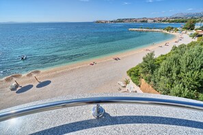 A coastal beach with clear waters, sun loungers, and umbrellas. - Sunset Split Rooms (Podstrana)