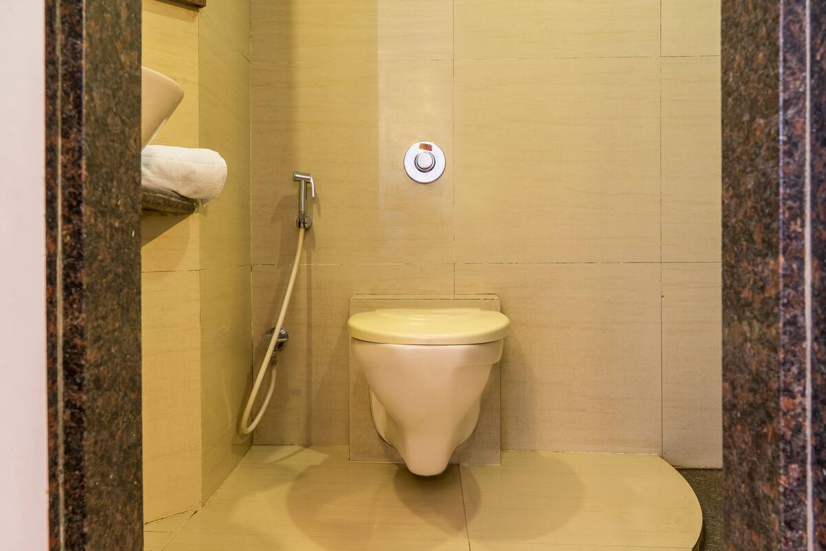 A small, compact bathroom with a toilet, a shower, and a towel rack.
