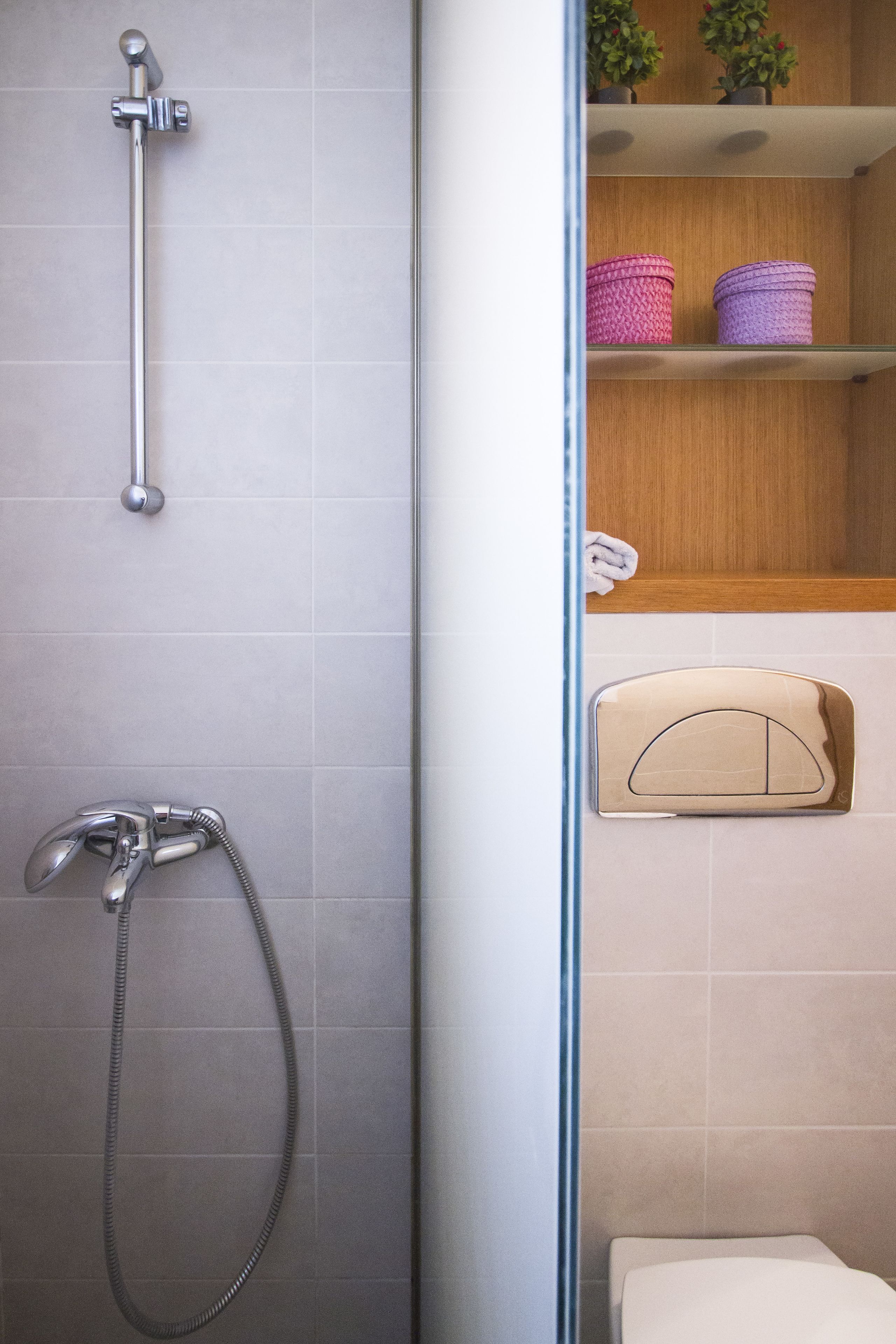Ein Badezimmer mit Dusche, Toilette und einem Regal mit Topfpflanzen.