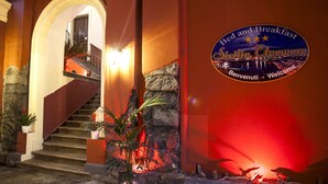 A hotel entrance with a staircase, a welcome sign, and potted plants. - Sicilia Etna Mare (Riposto)