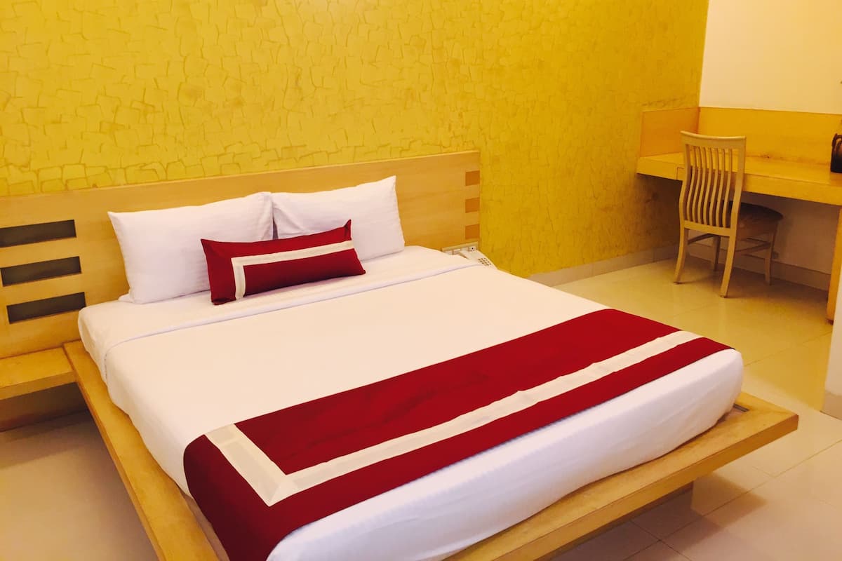 Una habitación de hotel con cama, escritorio y silla.