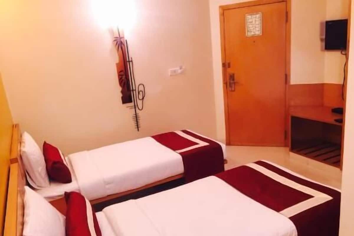 Una habitación de hotel con dos camas, una puerta de madera y un televisor montado en la pared.