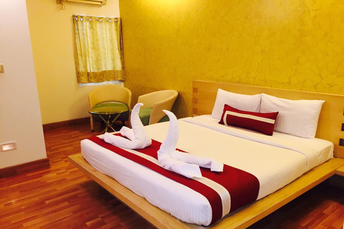 Una habitación de hotel con una cama, una silla, una mesita y una cortina.