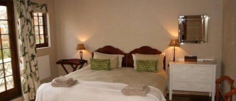 A bedroom with a bed, bedside tables, a dresser, and a mirror.