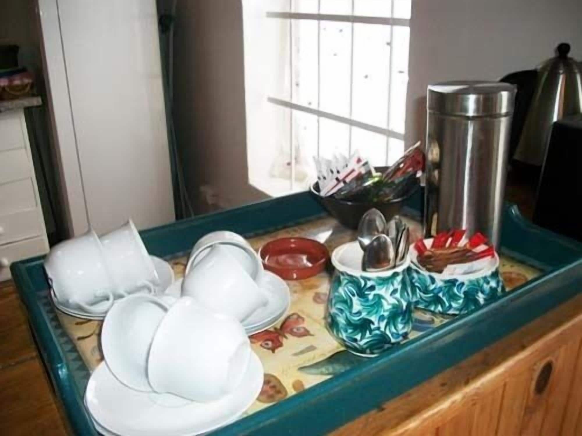 A buffet setup with white plates, a red bowl, and a coffee pot on a tray.