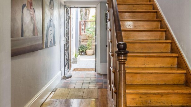 Una escalera de madera con barandilla que lleva a un piso superior.