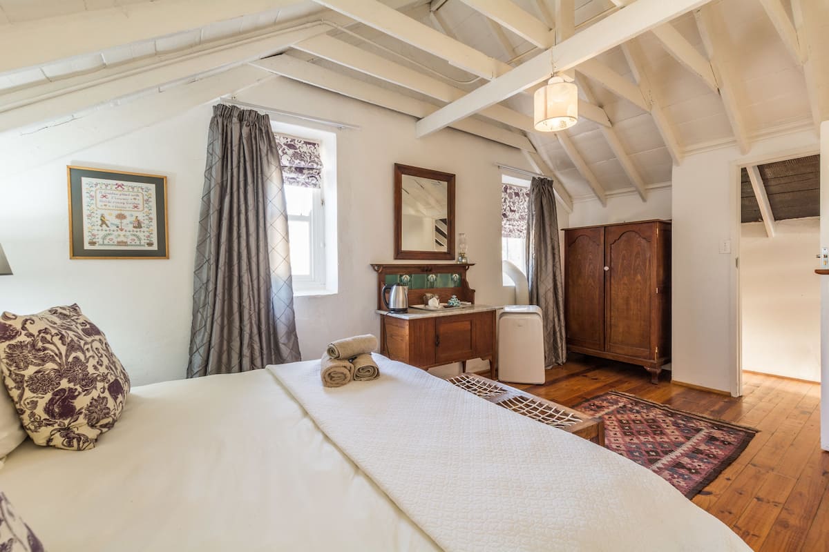 A bedroom with a bed, a dresser, a mirror, a radiator, and a wardrobe.