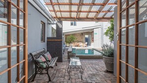 Un patio exterior con piscina, una banca y una mesa.