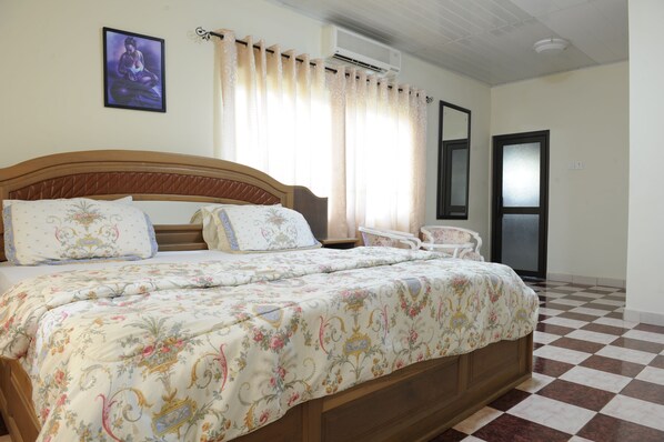 A bedroom with a bed, a chair, a picture on the wall, and a door. - Mount Pleasant Inns & Apartment (Obosomase)