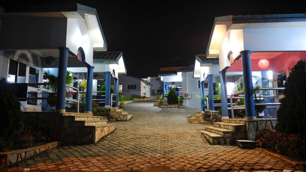 A nighttime view of a hotel with a cobblestone pathway leading to the entrance. - Mount Pleasant Inns & Apartment (Obosomase)