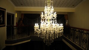 A grand chandelier in a spacious hall with a high ceiling and ornate railings. - Mount Pleasant Inns & Apartment (Obosomase)