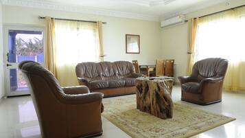 A living room with a brown leather sofa, two leather armchairs, a wooden coffee table, and a patterned rug.