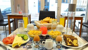 A breakfast table with various food items, including bread, eggs, and fruits. - Greta Apartments (Hersonissos)