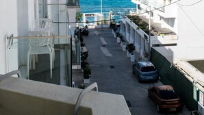 A narrow street with white buildings, a clear blue sky, and the ocean in the background. - Greta Apartments (Hersonissos)