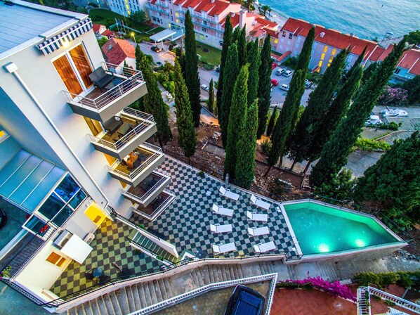 Un hôtel à plusieurs étages doté d’une piscine sur le toit, d’un espace extérieur aménagé et offrant une vue sur la mer.