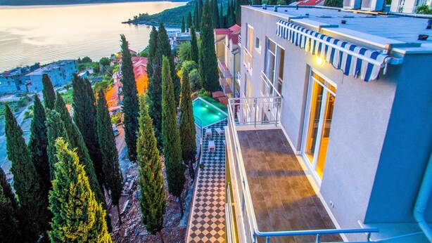A hotel with a pool, a view of the lake, and mountains in the background. - Apartments Didan (Konavle)