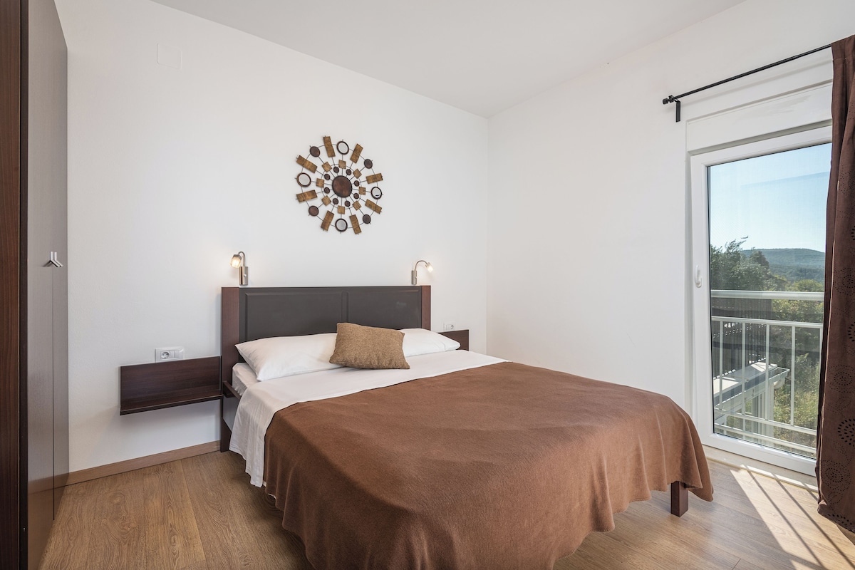 Habitación de hotel con cama, un adorno en la pared, ventana con cortinas y vistas al exterior.