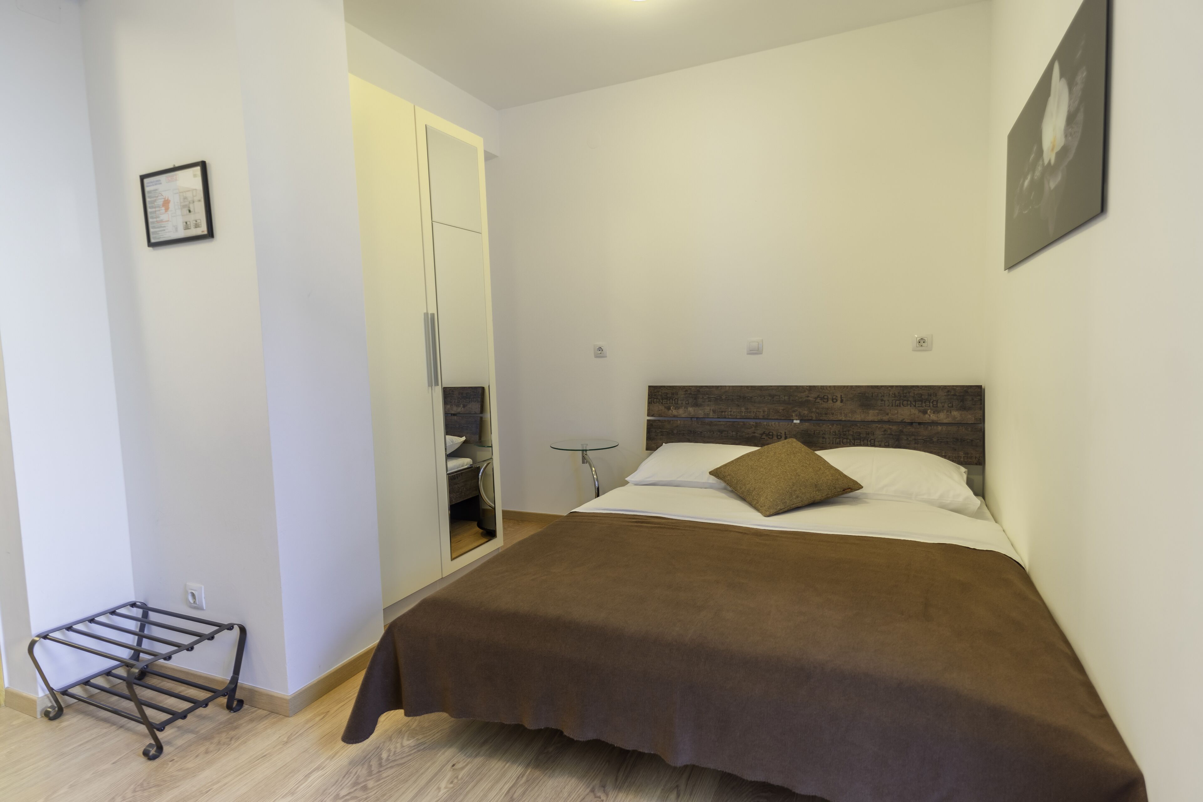 Un dormitorio con cama, mesita de noche, espejo y armario.