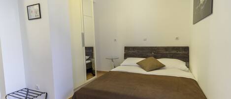 A bedroom with a bed, a bedside table, a mirror, and a wardrobe.