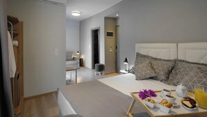 A modern hotel room with a large bed, bedside table, and a breakfast tray with pastries, coffee, and juice. - Skianthion (Skiathos)