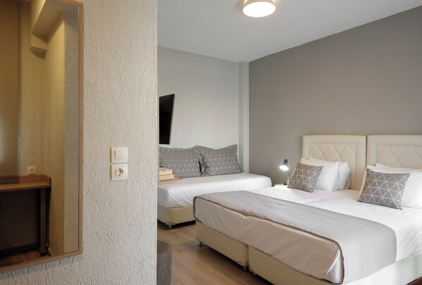 Habitación de hotel con dos camas, un espejo grande y una mesita de noche de madera.