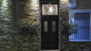 A stone building with a dark wooden door, two potted plants, and a balcony with a metal railing. - Skianthion (Skiathos)