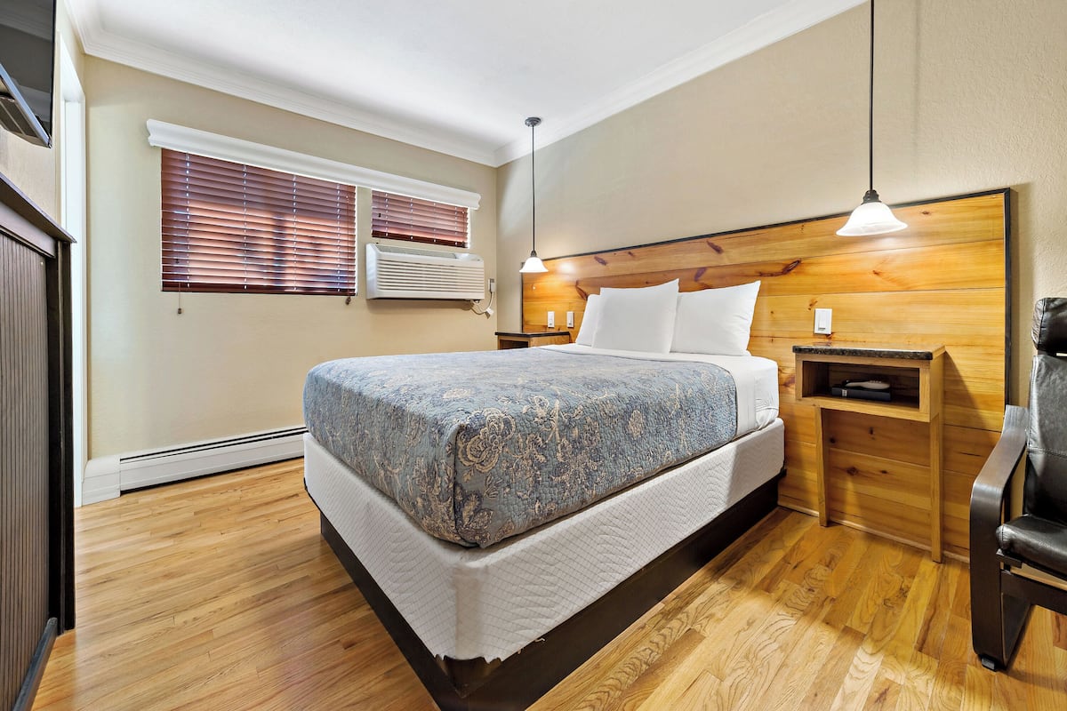 Une chambre à coucher avec un lit, une tête de lit en bois, des tables de chevet et un luminaire suspendu.