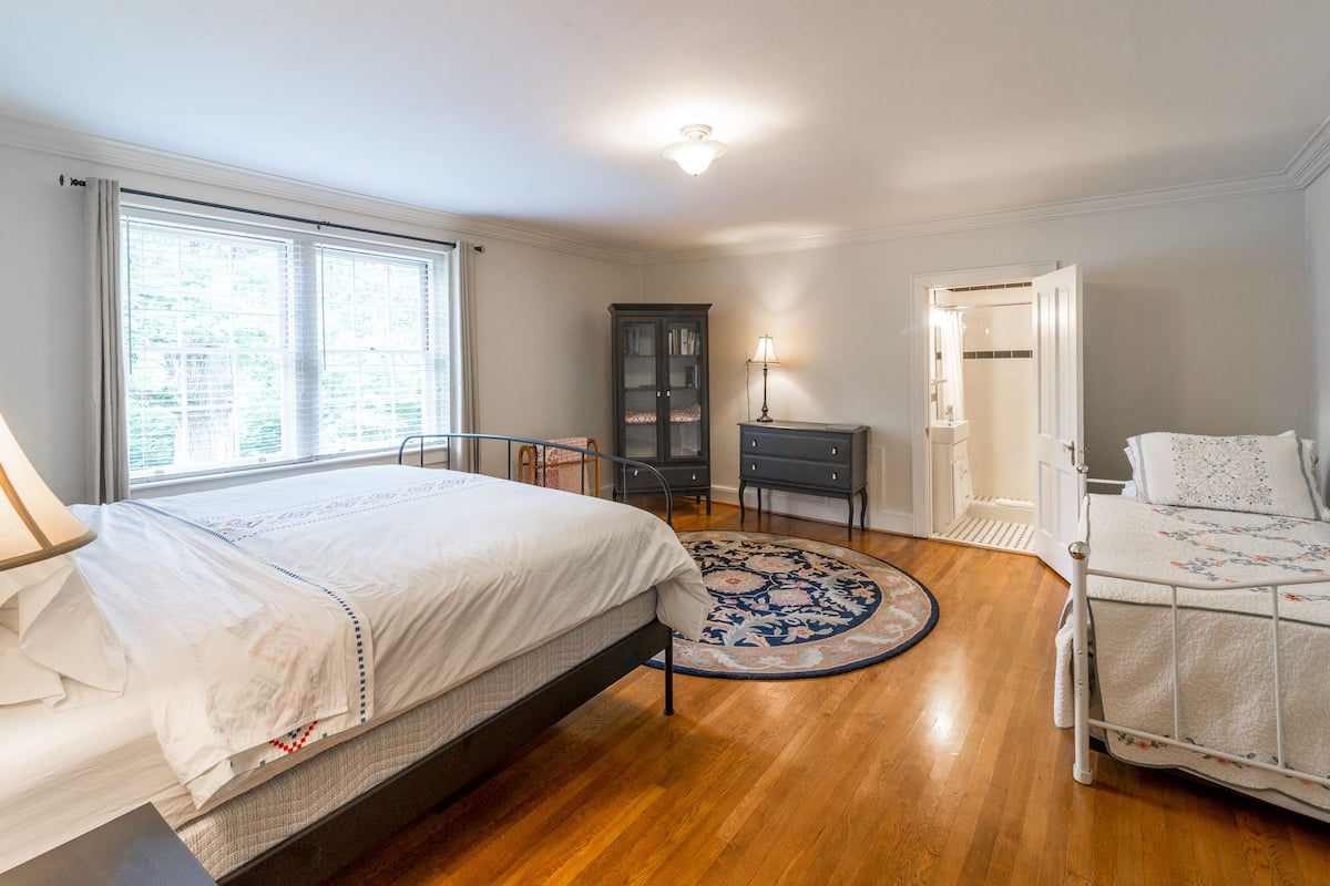 Une chambre à coucher comprenant un grand lit, un lit plus petit, une table de chevet, une armoire et un dressing.