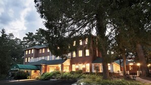 Un hôtel de deux étages, avec une façade en briques, de nombreuses fenêtres et une entrée abritée.