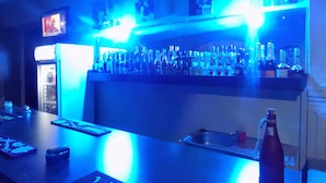 A bar area with a counter, shelves of bottles, and a refrigerator. - Posh Apartments (Lagos)