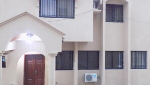 A building with a central door, multiple windows, and an air conditioning unit. - Posh Apartments (Lagos)