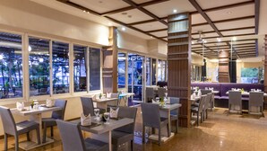Un interior de restaurante moderno con techos altos, ventanas amplias y una combinación de mesas de comedor y zonas de estar.