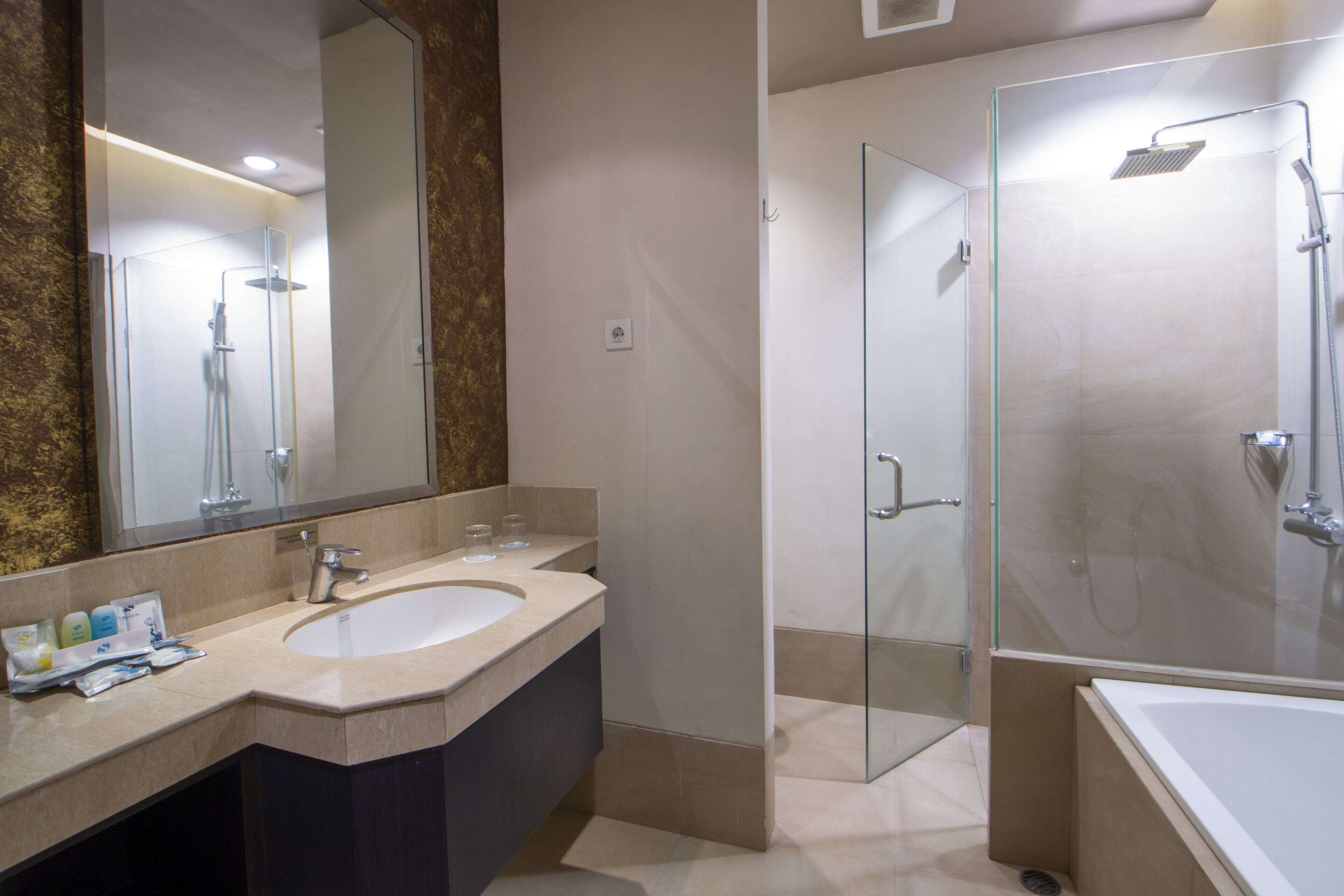 A modern bathroom with a large mirror, a sink, and a glass-enclosed shower area.
