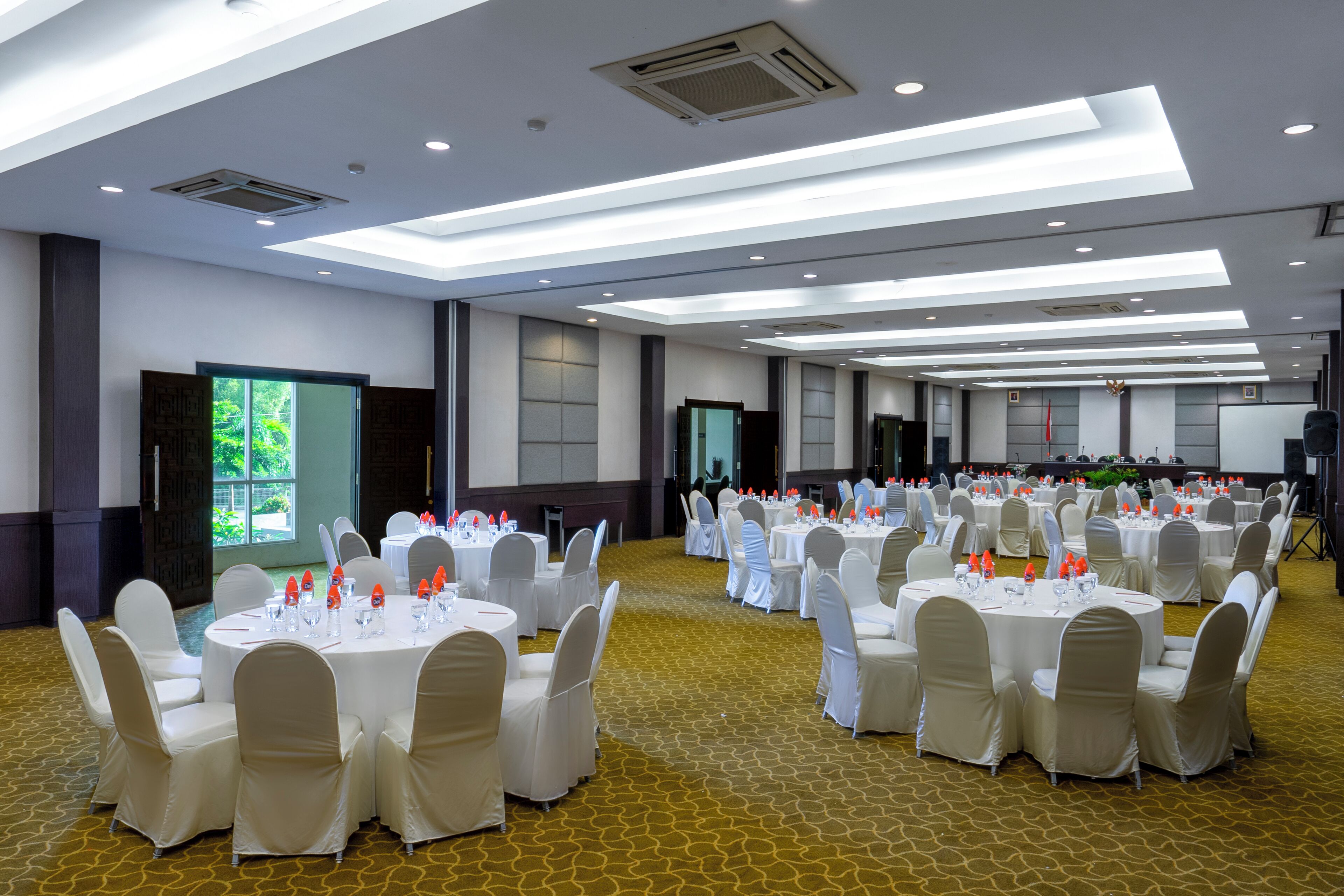 Un salón de banquetes con mesas redondas dispuestas para eventos, equipado con sillas y vajilla.