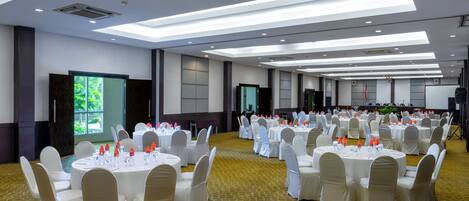 Un salón de banquetes con mesas redondas dispuestas para eventos, equipado con sillas y vajilla.
